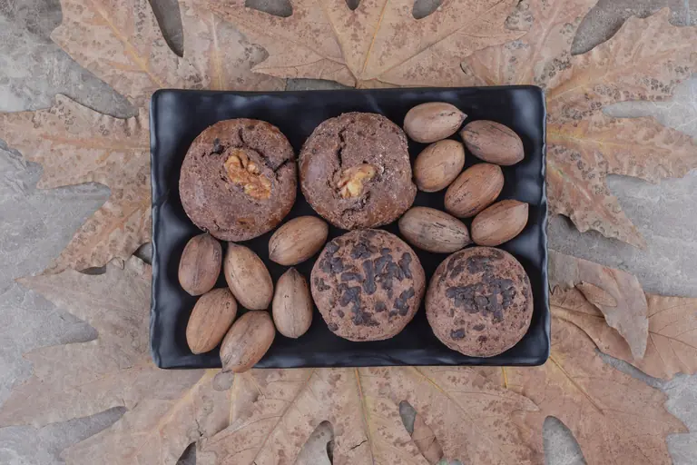 Cookies et noix de pécan sur un plat noir entouré de feuilles d'automne