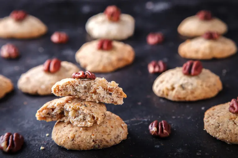 Cookies aux noix de pécan sur fond sombre, l'un cassé pour montrer l'intérieur