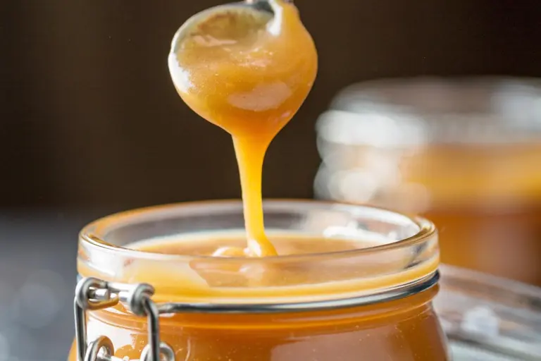 Caramel au beurre salé maison qui coule d'une cuillère dans un bocal
