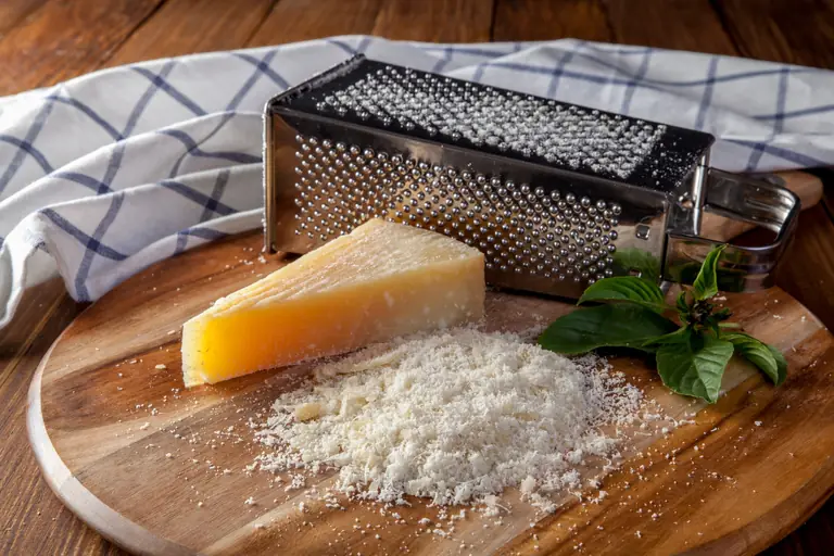 Parmesan fraîchement râpé sur une planche en bois avec une râpe